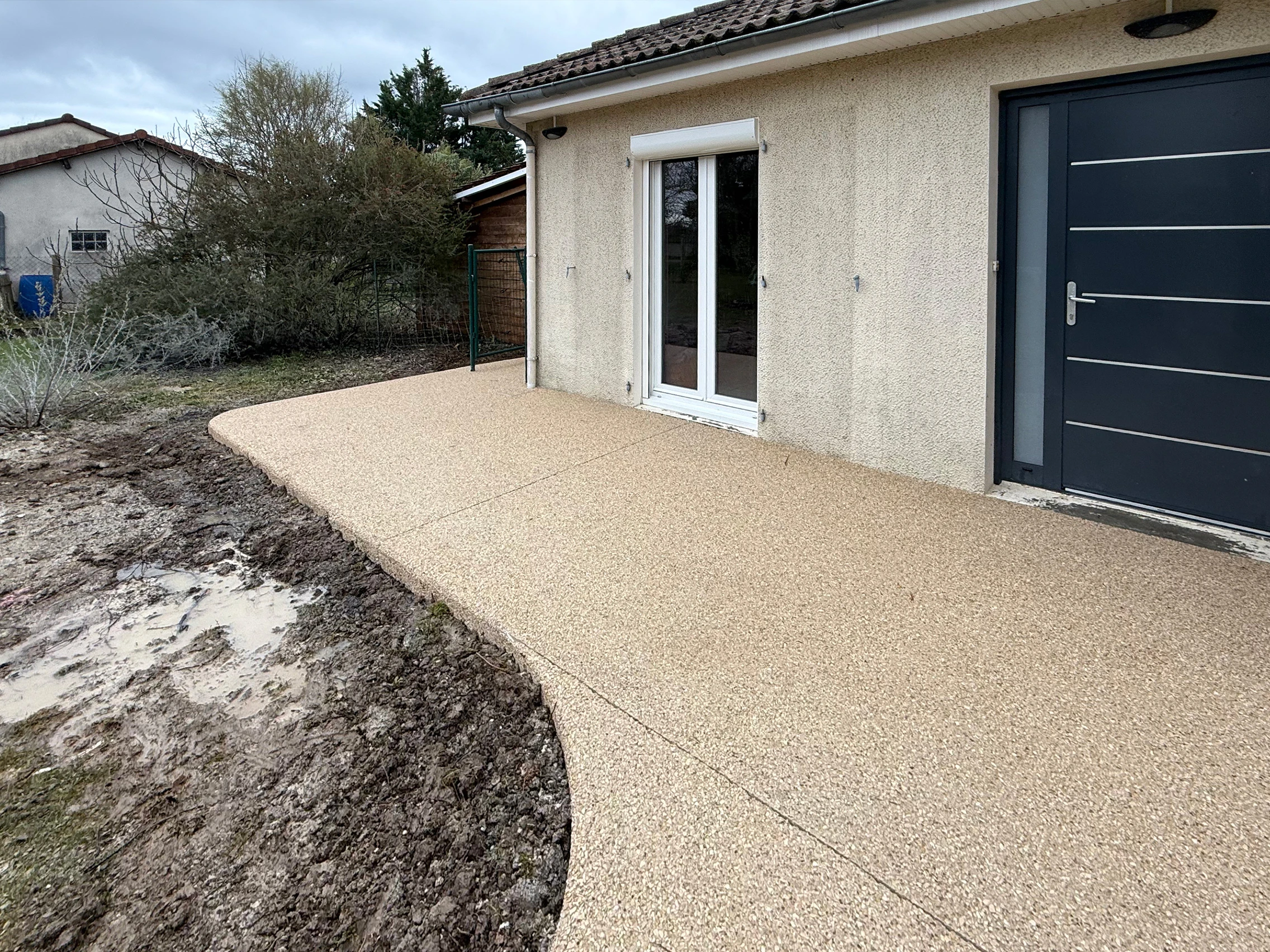 Terrasse en béton désactivé longeant les baies vitrées d'une maison