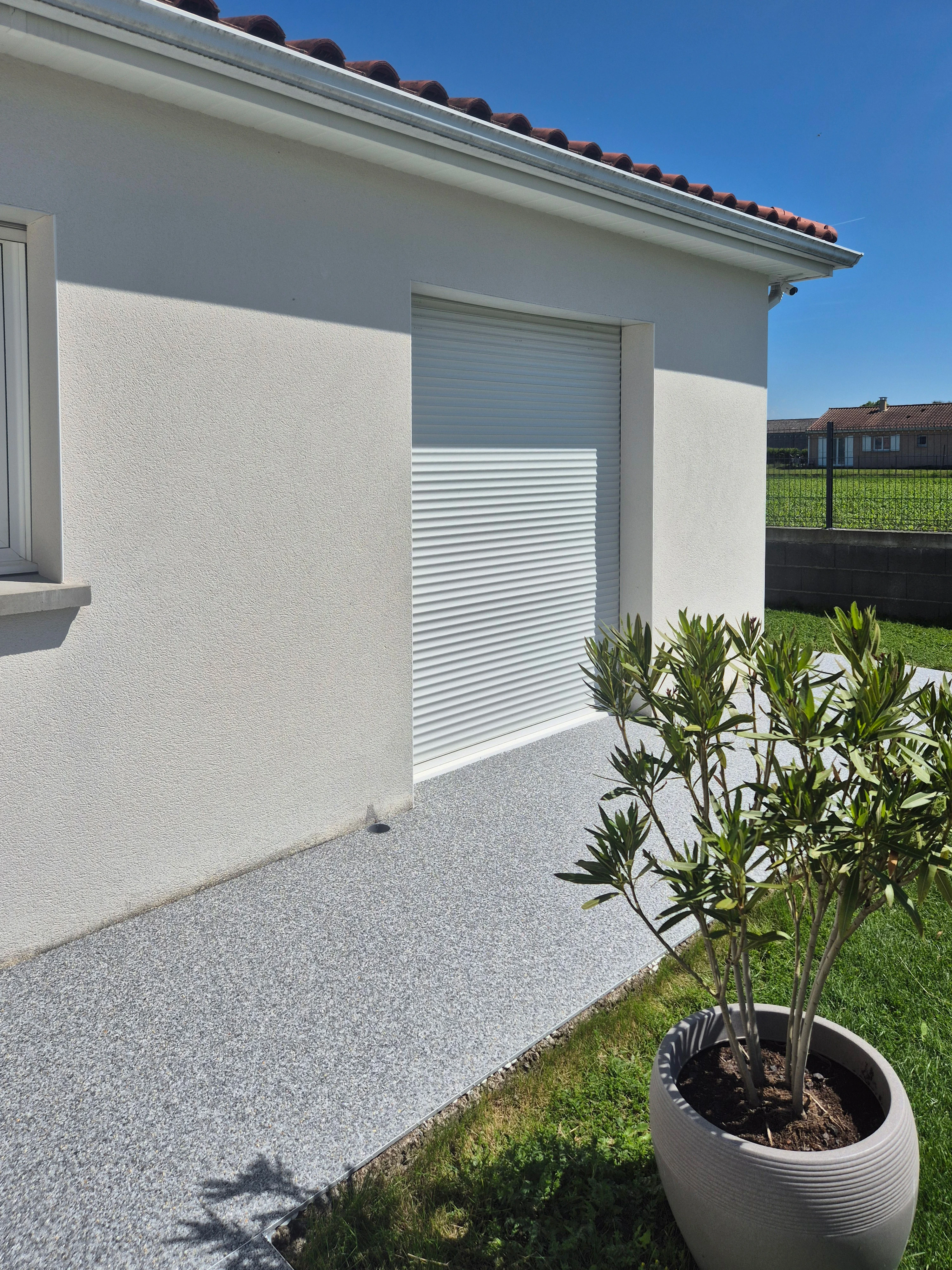 Allée en moquette de pierre grise devant un garage, finition drainante