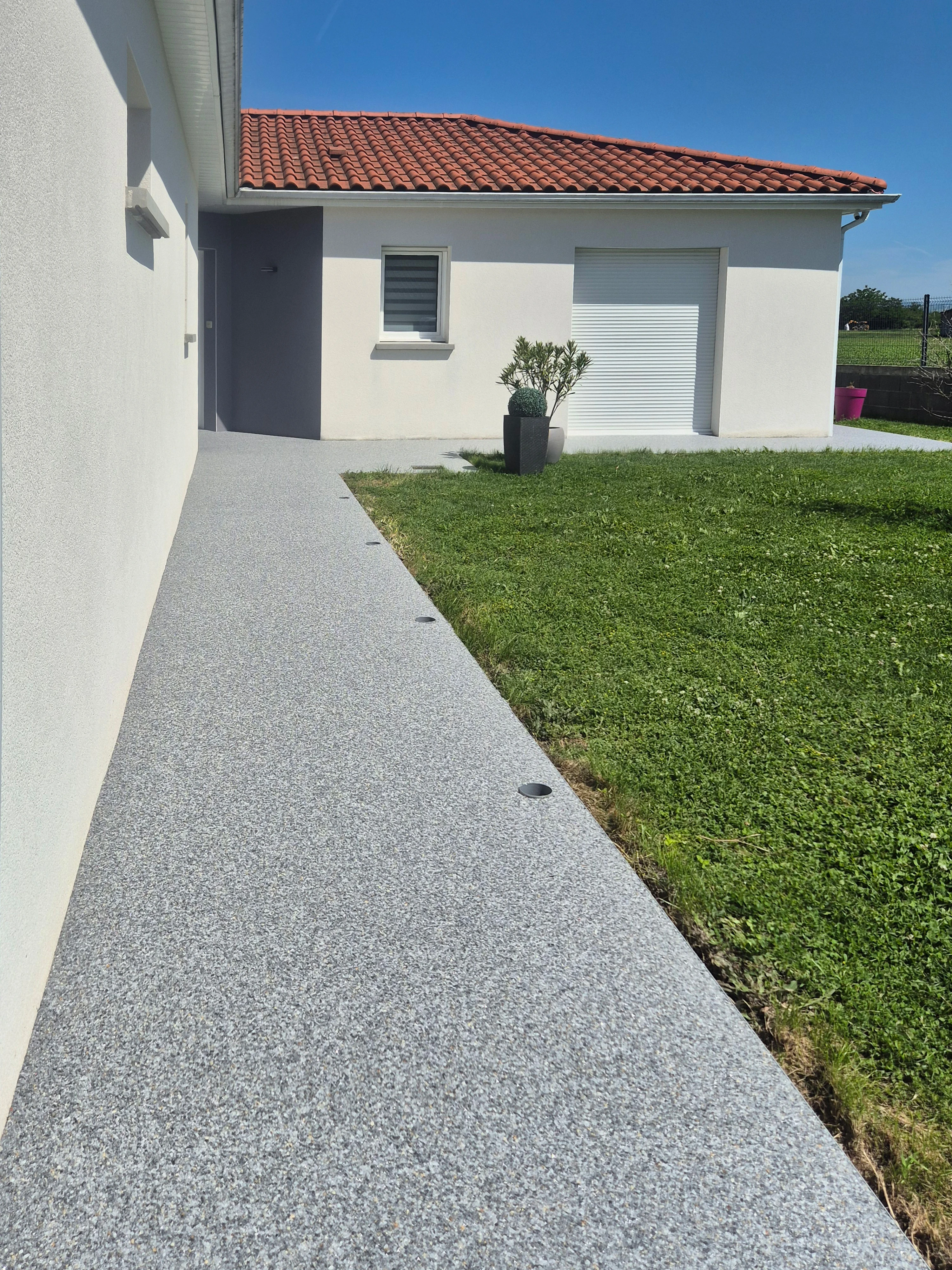Tour de maison en moquette de pierre grise avec plantation en pot